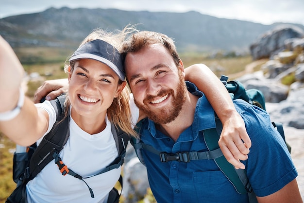 Hiking happy and couple taking a selfie by a mountain in nature while walking or trekking with freedom in Canada Smile memory and healthy woman loves taking pictures when traveling on fun holidays