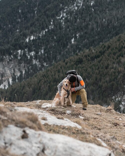 Hiking man with his golden retriever dog in mountain