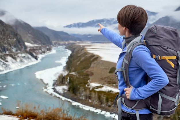 Hiking smiling woman with a backpack in mountains. Beautiful young woman is traveling in the mountains.