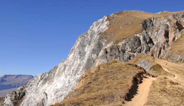 Hiking trail in high altitude in the Alps rocky mountains under clear blue sky