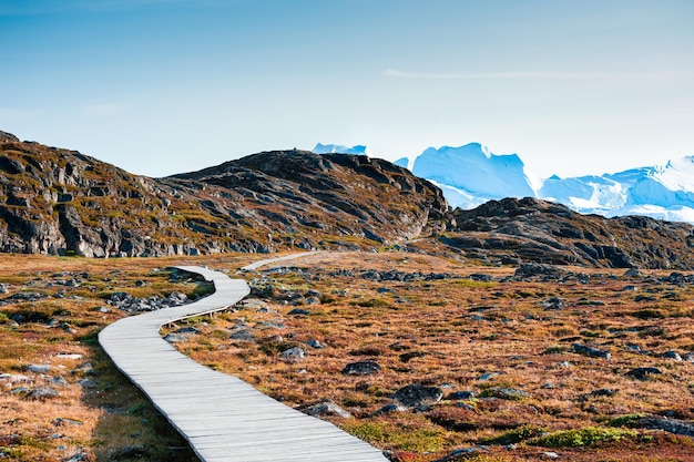 Hiking trail to the Ilulissat icefjord with big icebergs at sunset western Greenland