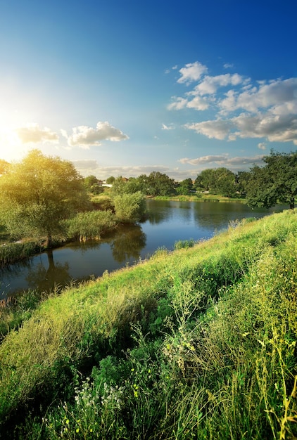 Hill with green grass near river at sunlight