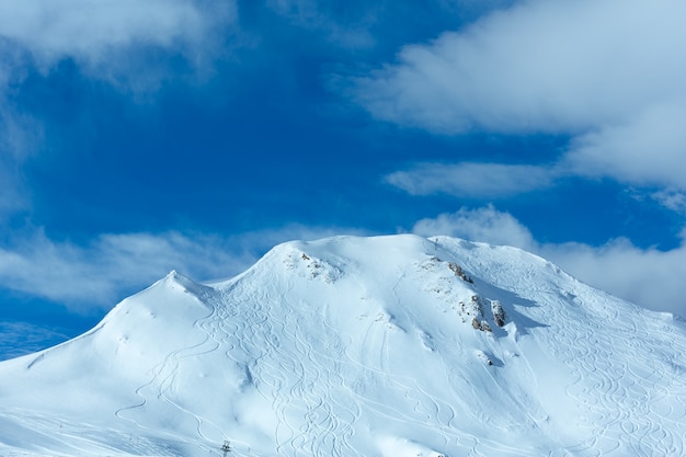 Hillside undulate ski tracks and clouds in the blue sky. Winter Austria.