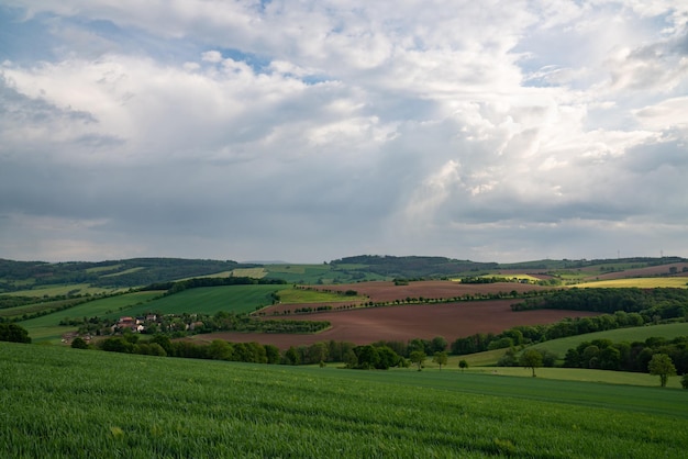 Hilly area in Saxony near Dresden Landscape with green fields and meadows Houses are visible in the distance Dark sky and many clouds Before sunset