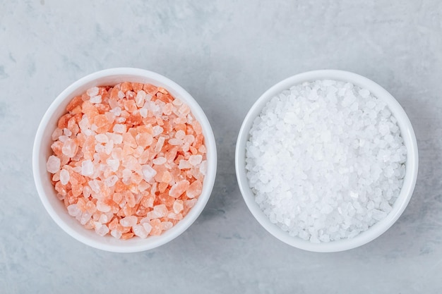 Himalayan Crystal Salt in white bowls on gray stone background