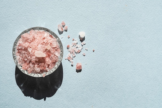 Himalayan pink salt in glass bowl placed on blue background