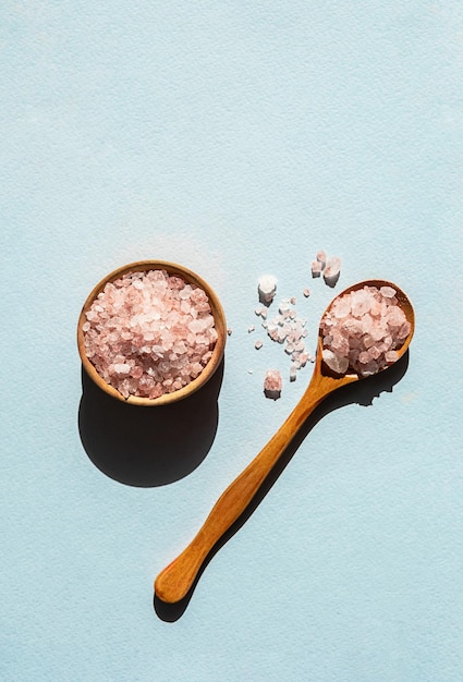 Himalayan pink salt in wooden spoon placed on blue background