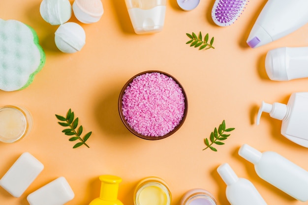 Himalayan salt bowl with cosmetics products on colored background