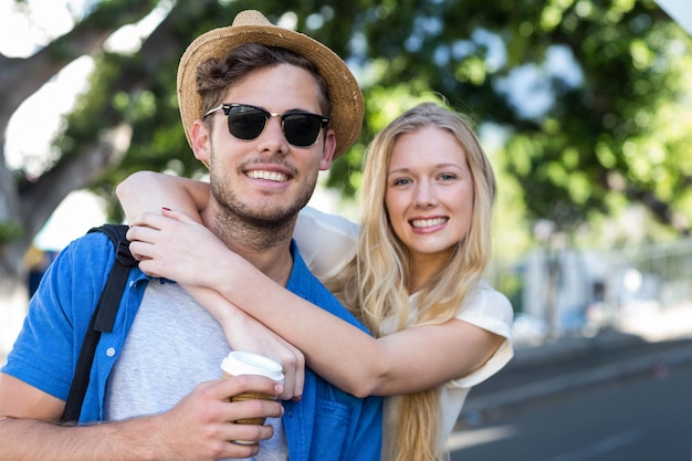 Hip couple embracing and smiling at the camera outdoors