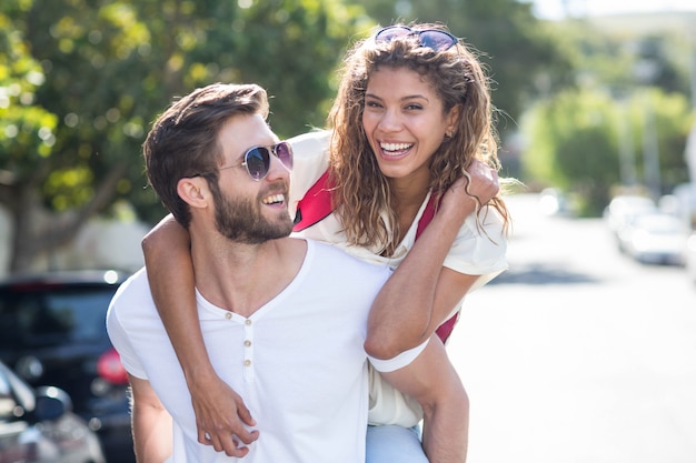 Hip man giving piggy back to his girlfriend on the street