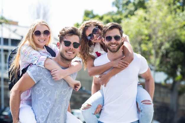 Hip men giving piggy back to their girlfriends on the street