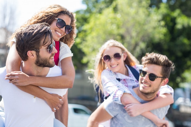 Hip men giving piggy back to their girlfriends on the street