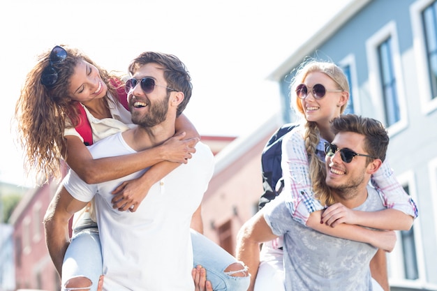 Hip men giving piggy back to their girlfriends on the street