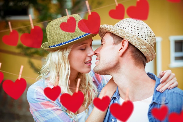 Hip young couple about to kiss against hearts hanging on a line