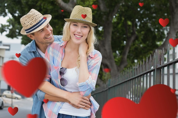 Hip young couple smiling at camera by railings against hearts