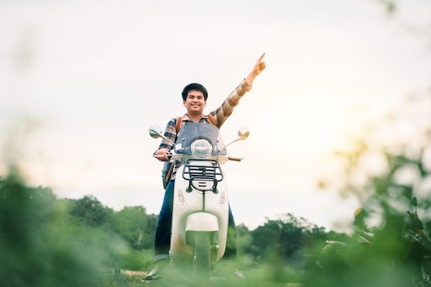 Hipster backpacker riding a motor scooter on road Travels by scooter slow life on vacation resting time