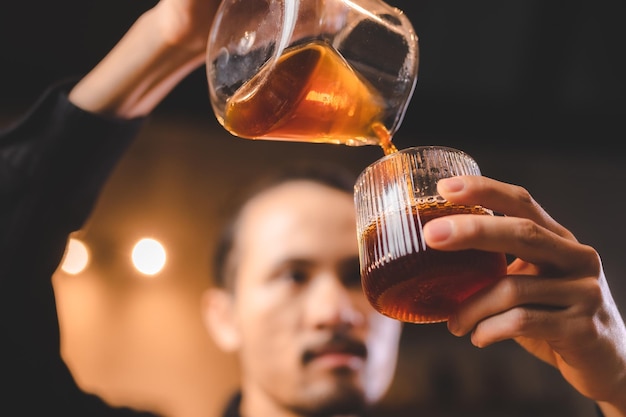 Hipster barista making a drink coffee with drip or filter style by pouring hot water to brew a caffeine beverage from black bean in cafe restaurant business shop using paper for aroma to a cup or mug