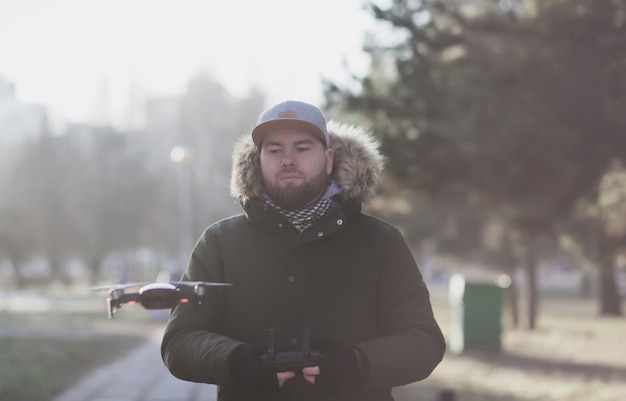 Hipster bearded man in cap with flying drone outdoors