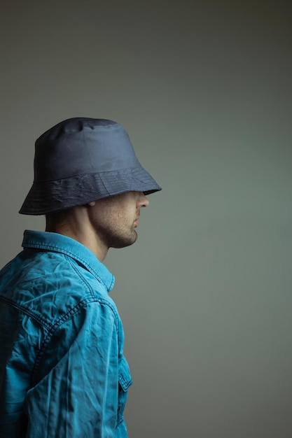 Hipster bearded man wearing a blue shirt and dark hat looking away