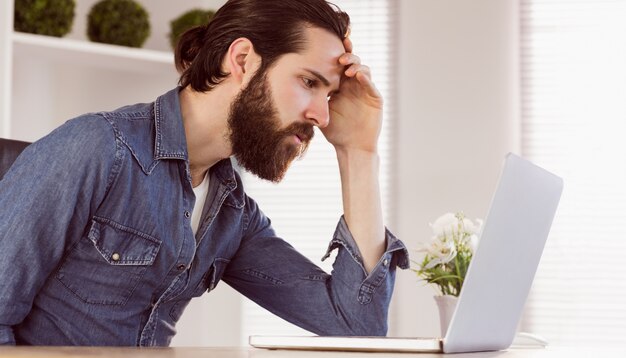 Hipster businessman looking at laptop