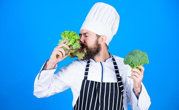 Hipster chief chef vegan cafe Health and dieting I choose vegan lifestyle Man cook hat apron hold broccoli and lettuce Vegan recipe concept Buy fresh vegetables grocery store Vegan restaurant