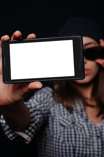 Hipster cool girl taking picture on smartphone selfportrait screen view snapshot studio on a black background Phone white screen