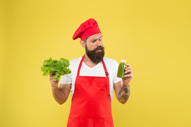 Hipster decide what to choose healthy eating and dieting concept cook hold fresh salad and smoothie in bottle organic eco vegan products bearded man chef in apron and hat cooking healthy food