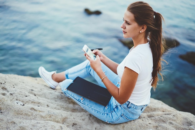 hipster girl browsing internet in roaming while enjoying free time at nature and looking away