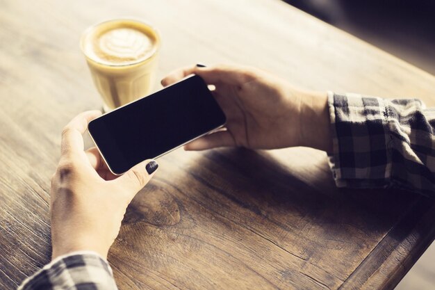 Hipster girl hands with cell phone and cup of coffee