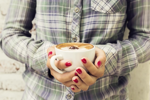 Hipster girl holding a cup of cappuccino