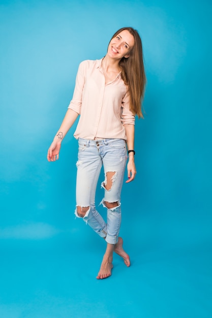 Hipster girl sitting on floor against blue background