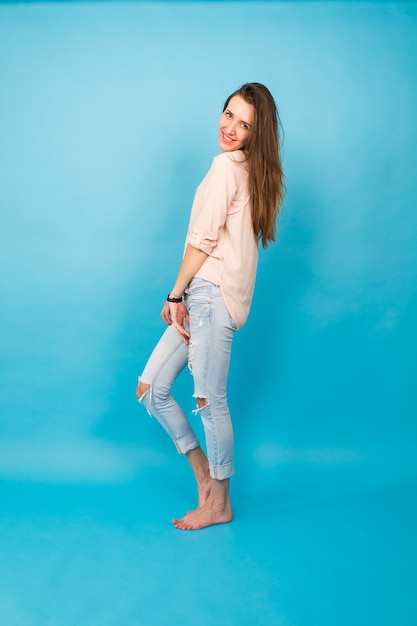 Hipster girl sitting on floor against blue background