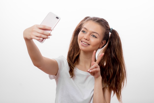 Hipster girl wearing two ponytails showing victory sign while taking selfie