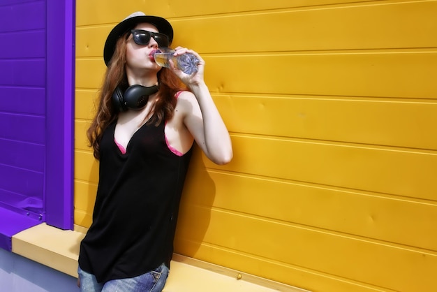 Hipster girl with headphones at the wall