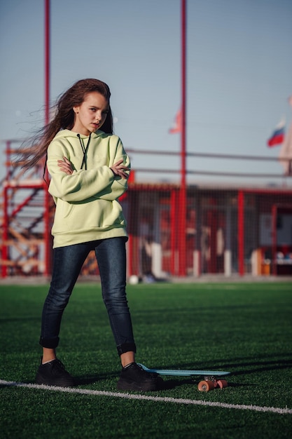 Hipster girl with skateboard outdoors Modern girl with a skateboard walking on a stadium Rest from study Outdoors Lifestyle