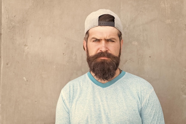 Hipster lifestyle Cool hipster with beard wear stylish baseball cap Brutal handsome mature hipster man Bearded man trendy style Barber salon and facial hair care Beard and mustache grooming