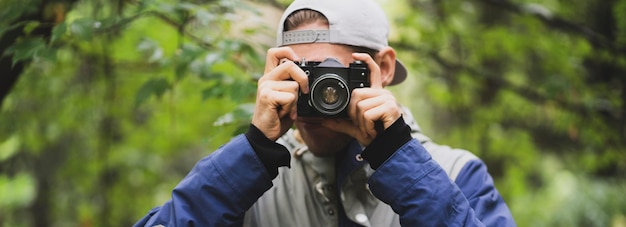 A hipster making photo using old vintage camera outdoors