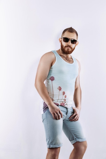 Hipster redhead bearded guy in sunglasses in summer looking at camera posing on white background