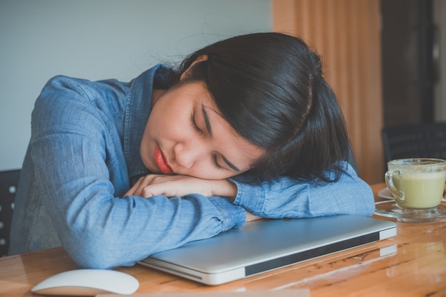 Hipster teenage sleeping on laptop at cafe looks tired after working.