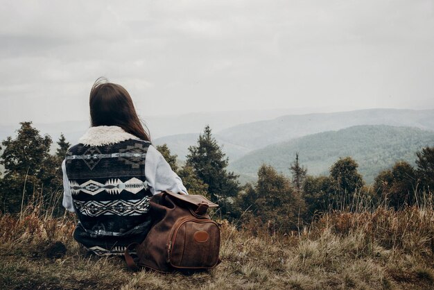 Photo hipster traveler with backpack relaxing on top of mountains looking forward wanderlust and travel concept with space for text stylish woman hiking atmospheric epic moment