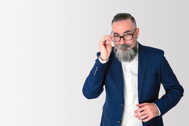 Hipster with big bearded blue jacket and white shirt, lowering his glasses to look over them with a serious face