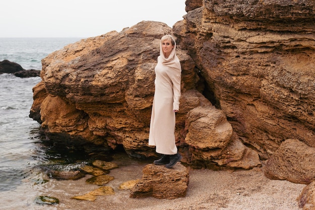 Hipster woman enjoys looking at water while walking on the beach near the sea