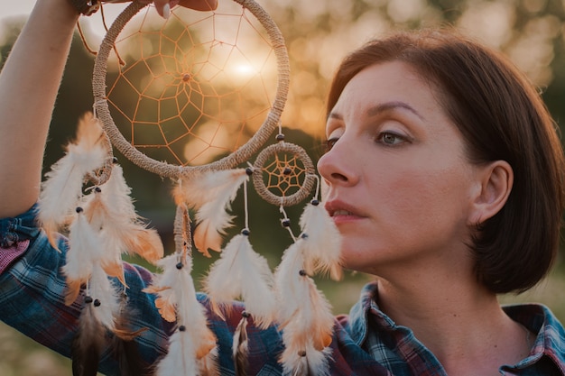 Hipster woman in the form of a Shaman is looking for inspiration from mother Earth in a wigwam in nature.