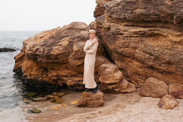 Hipster woman walking near sea Female model with short hair having walk on cloudy day Nature spare time concept