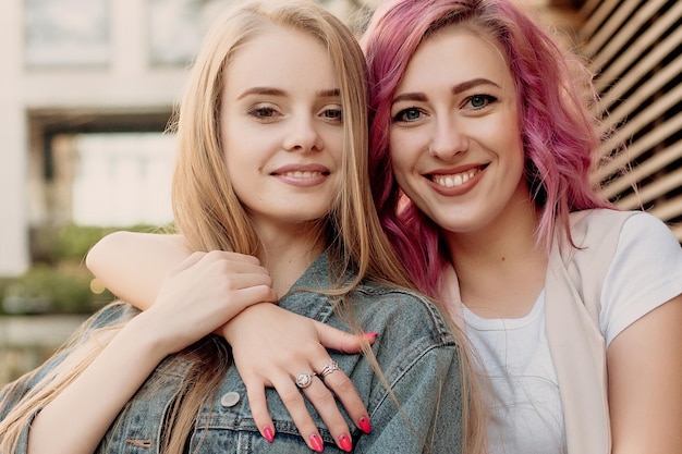 Hipster young adult friends embracing while hanging out in the city Two young women laughing and walking enjoying carefree vacation lifestyle