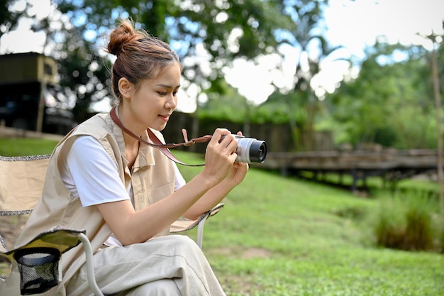 Hipster young Asian female taking a picture of the beautiful forest with her retro film camera