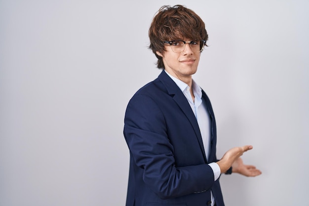 Hispanic business young man wearing glasses inviting to enter smiling natural with open hand