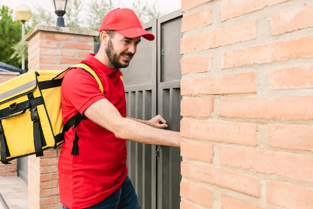 Hispanic delivery man in red uniform ringing the bell to delivery packages Deliver service and small business concept