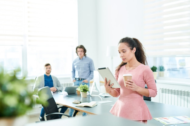 Hispanic female manager reading business article on tablet