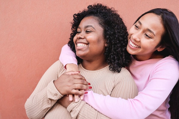 Hispanic girls laughing together and hugging each other outdoor - Focus on left woman face